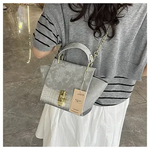 Detailed close-up of grey handbag featuring marble and crocodile textures with gold hardware