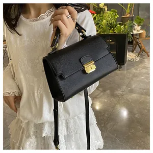 Detail of black lychee texture leather bag with gold square rotary lock and handle