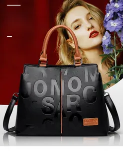 Close-up of black lychee-textured tote bag with brown handles and embossed letters
