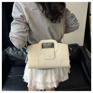 Détail du sac beige motif crocodile avec chaîne dorée et poignée découpée moderne