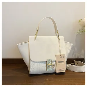 Detail of white handbag with crocodile texture panels and elegant gold ring hardware