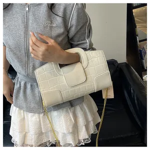 Détail du sac crème à motif crocodile avec chaîne dorée et poignée ronde rigide