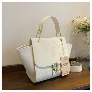 Detailed view of crocodile pattern texture and golden rotating lock on cream handbag