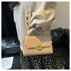 Detail of light beige crossbody bag showing lychee grain leather and gold metal buckle