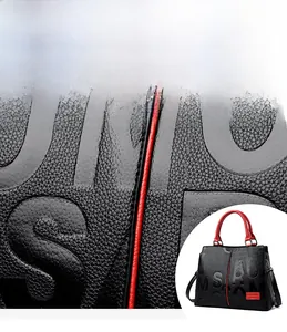 Detail of high-quality embossed black leather fabric with red edges and metal plaque