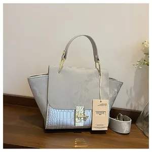Detail of gray handbag featuring matte texture, crocodile pattern leather and gold hardware