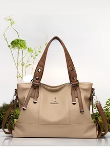 Detail of light brown lychee grain leather tote bag with metallic bird logo and rivets