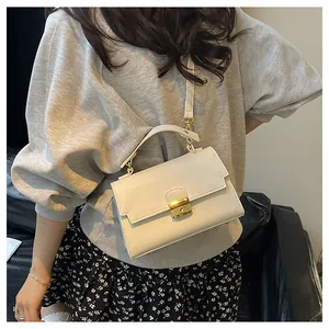 Detail of cream leather shoulder bag with lychee texture and gold metal buckle closure