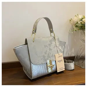 Detail of matte textured flap and crocodile embossed leather on a grey vintage handbag