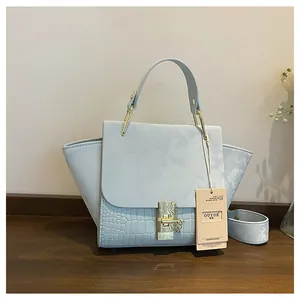 Close-up of light blue frosted wing bag with crocodile texture and gold lock