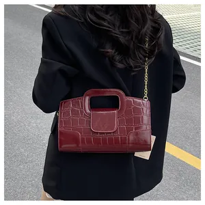 Détail du sac en cuir crocodile bordeaux avec chaîne en métal et poignée supérieure