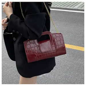 Détail d'un sac à main rouge foncé en similicuir embossé crocodile et chaîne dorée