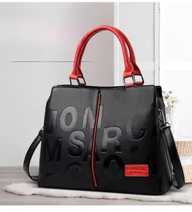 Close-up of black litchi grain handbag with red handles and embossed classic logo