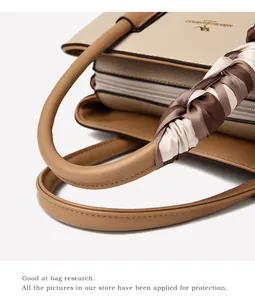 Close-up of beige lychee leather handbag with silk scarf detail and brown handles