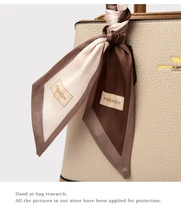 Detail of beige lychee leather handbag with golden logo and printed silk scarf handle