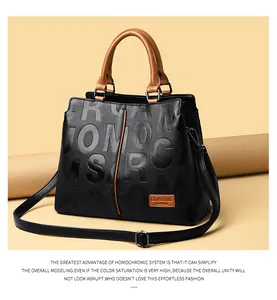 Detail of black leather tote bag featuring large embossed lettering and brown top handles