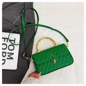 Dettaglio borsa trapuntata verde brillante con manico in bambù dorato e chiusura in metallo