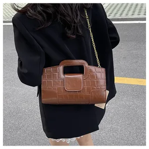 Détail du sac bandoulière marron foncé à motif crocodile avec chaîne dorée et anse