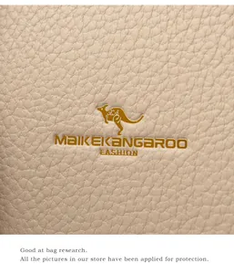Macro view of beige lychee grain leather handbag with gold kangaroo metal logo