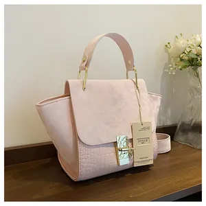 Detail of pink wing bag with matte suede texture and crocodile embossed leather