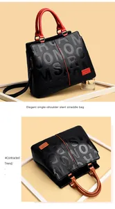 Detail of black pebbled leather handbag with red handles and JONOMSRE embossed texture