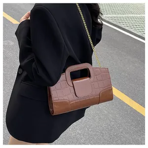 Détail du sac à main en cuir à motif crocodile marron foncé avec chaîne dorée
