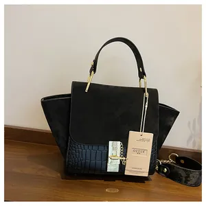 Detail of black matte and crocodile texture handbag with gold buckle and shoulder strap