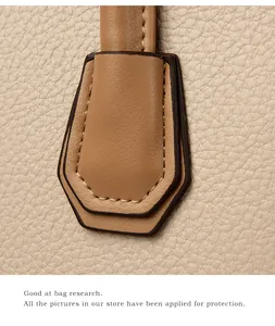 Macro shot of lychee grain leather texture and precise stitching on beige handbag