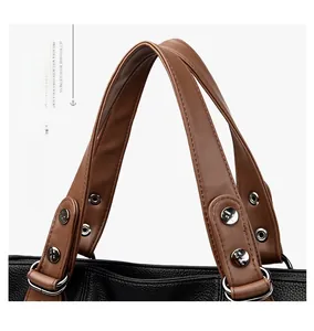 Close-up of brown leather handles with silver rivets on a black lychee texture handbag