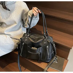 Dettaglio della borsa tote in pelle nera martellata con doppi manici e rifiniture a cerniera