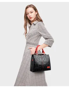 Detailed view of black and red leather tote bag with stylish embossed letters on model