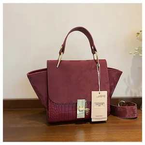 Detail of burgundy textured satchel with crocodile embossing and gold metal clasp lock