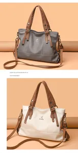 Detail of cross-body tote bag showing lychee grain texture and metal bird logo