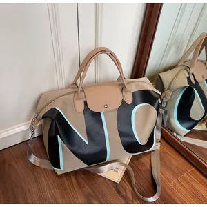 Detail of khaki travel bag with NC letters, leather handles and adjustable shoulder strap