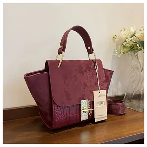 Detail of burgundy crocodile pattern leather and matte suede wing bag with gold lock