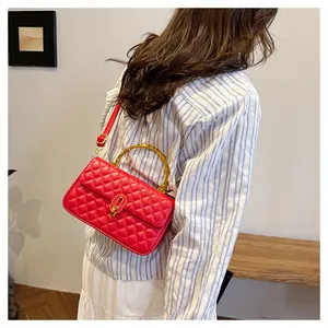 Borsa trapuntata rossa in pelle con manico in bambù indossata da una modella in casa