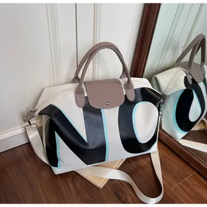 Detail of canvas travel bag with NO letter print and brown leather handles and strap