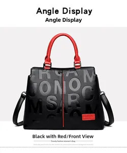 Detail view of black textured leather handbag with red contrast handles and classic silver hardware
