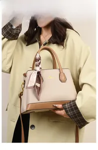 Close-up of beige litchi grain tote with brown trim and silk scarf on a trench coat model