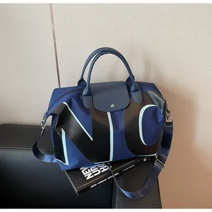 Detail of navy nylon travel bag with NYC print on leather sofa with urban lifestyle book