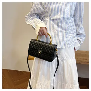 Dettaglio della borsa trapuntata nera con manico dorato decorativo a forma di bambù
