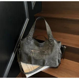 Detail of dark grey frosted leather tote bag with functional zippers and wide straps