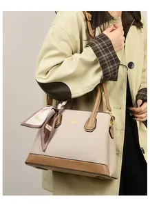 Detail of two-tone lychee leather handbag with kangaroo metal logo and silk scarf handle