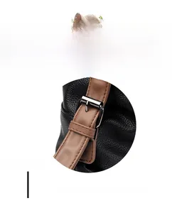 Detail of black litchi grain leather bag with brown strap and silver buckle