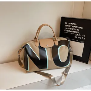 Detail of khaki canvas travel bag featuring leather handles and bold 'NO' letter print
