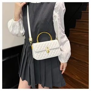 Dettaglio di una borsa a tracolla trapuntata bianca con manici in bambù dorato