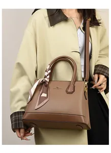 Detail of lychee pattern leather tote bag with decorative scarf and gold kangaroo logo