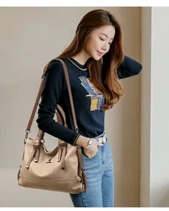 Detail of beige leather crossbody handbag with contrasting brown straps and metal hardware