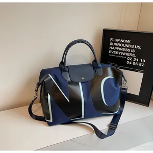 Detail of blue canvas travel bag with black leather handles and large NO letter print