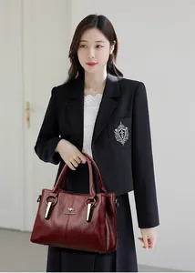 Gros plan du sac à main en cuir bordeaux avec logo kangourou et détails de la marque